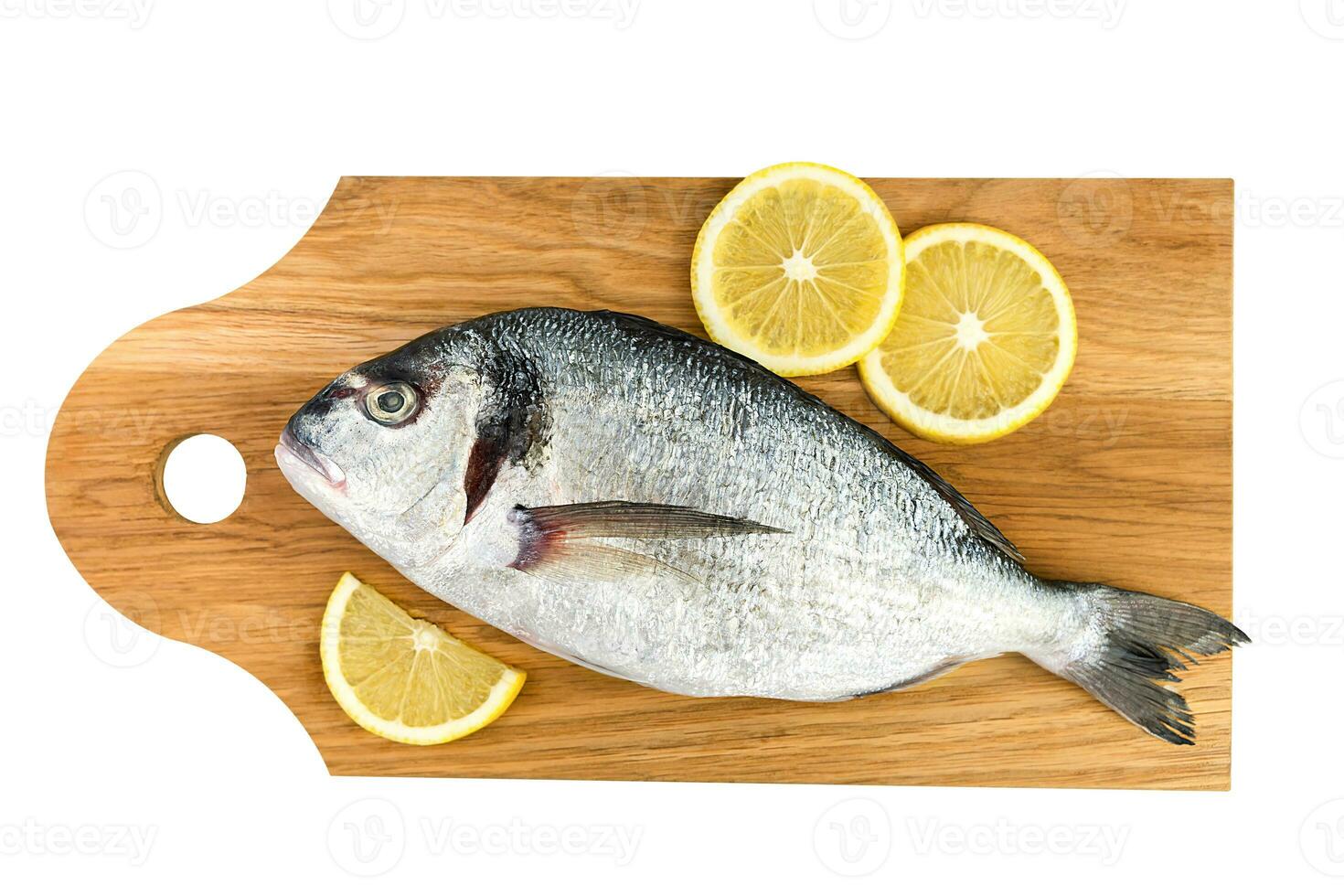 Raw fish Dorado with lemon on a cutting board isolated on a white background. Top view. photo