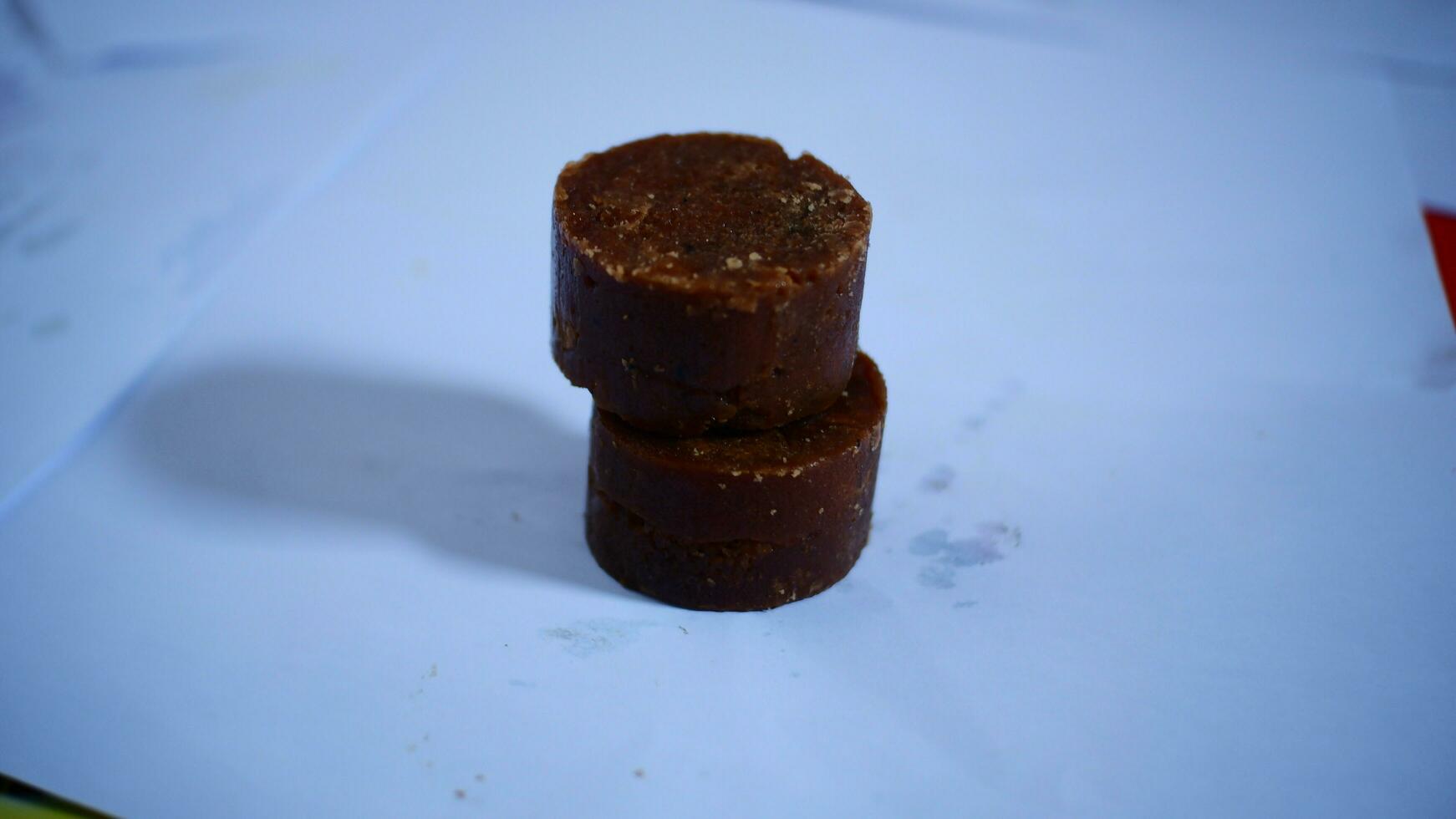 black cylindrical palm sugar isolated on white background, top view photo
