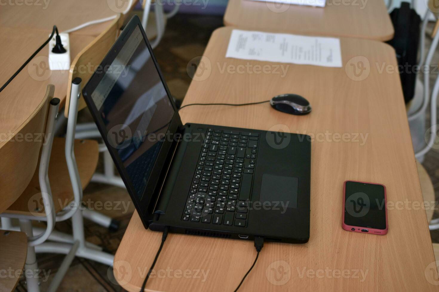 A black laptop and a phone on the desktop. An office workplace with a computer. photo