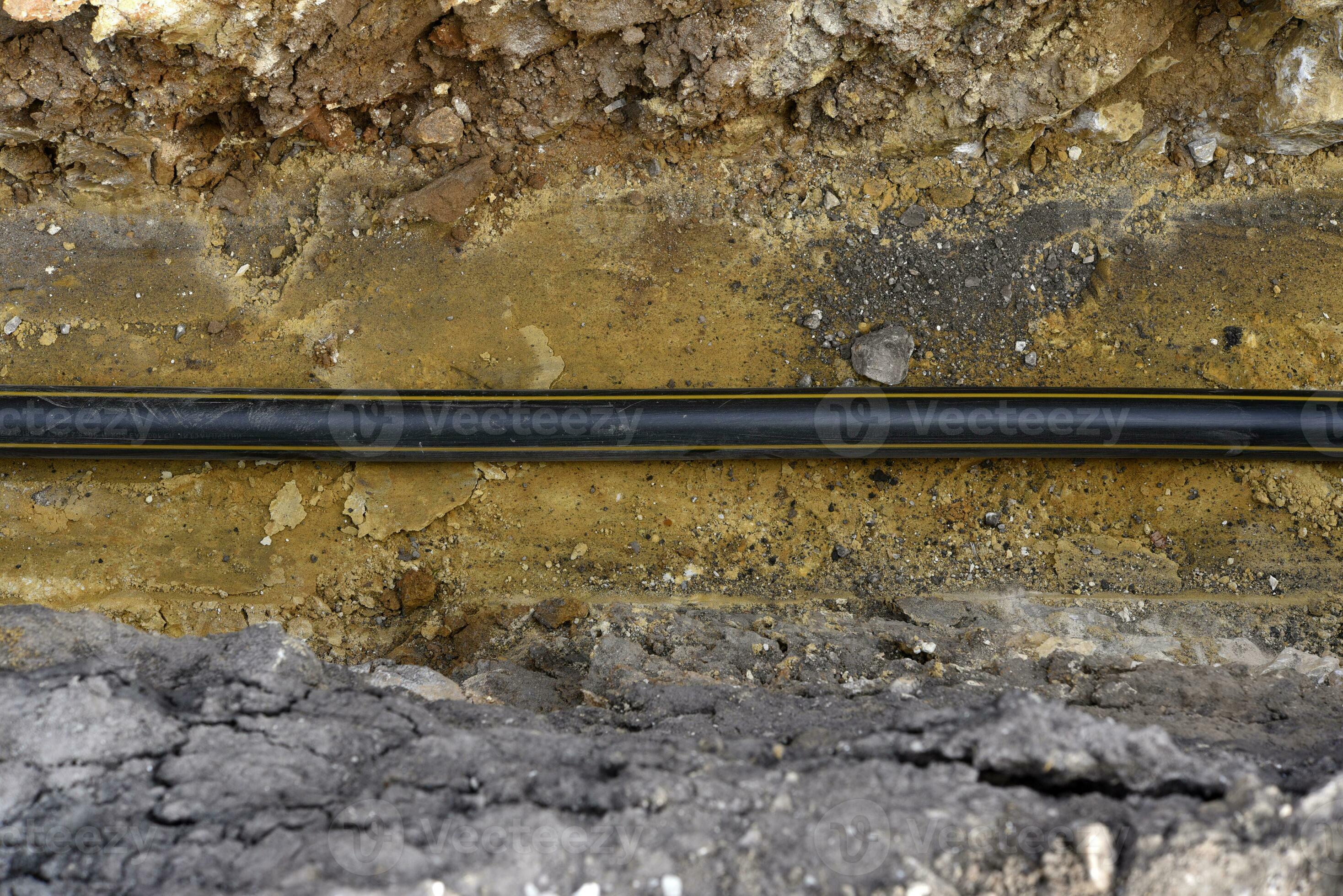 A plastic black gas pipe at the bottom of the trench. A dug trench for