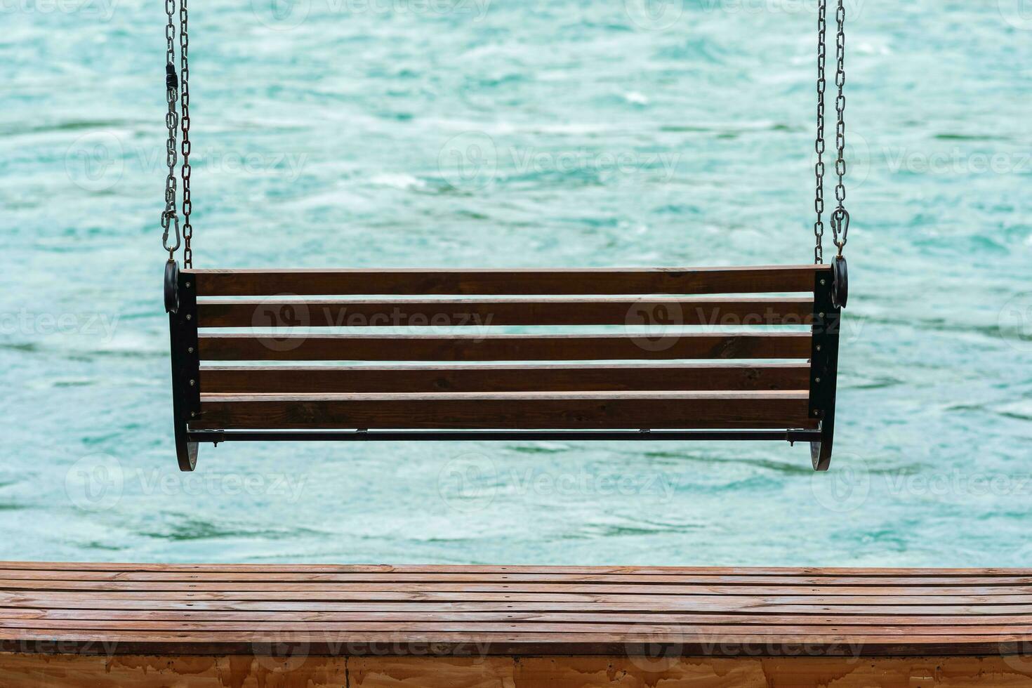 bench-swing over water on the bank of a fast river photo