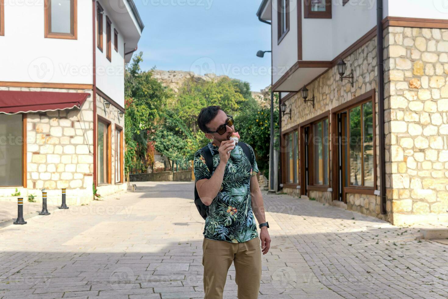 turista comer hielo crema en el calle de un Mediterráneo pueblo foto