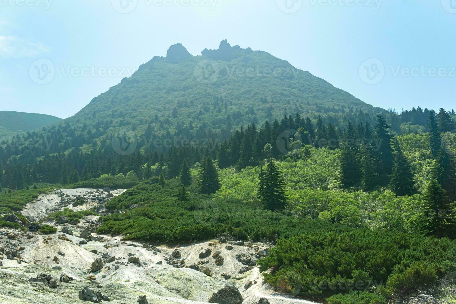 peak with the crater of the Mendeleev volcano on the island of Kunashir is visible through the atmospheric haze from a slope with a fumarole field photo