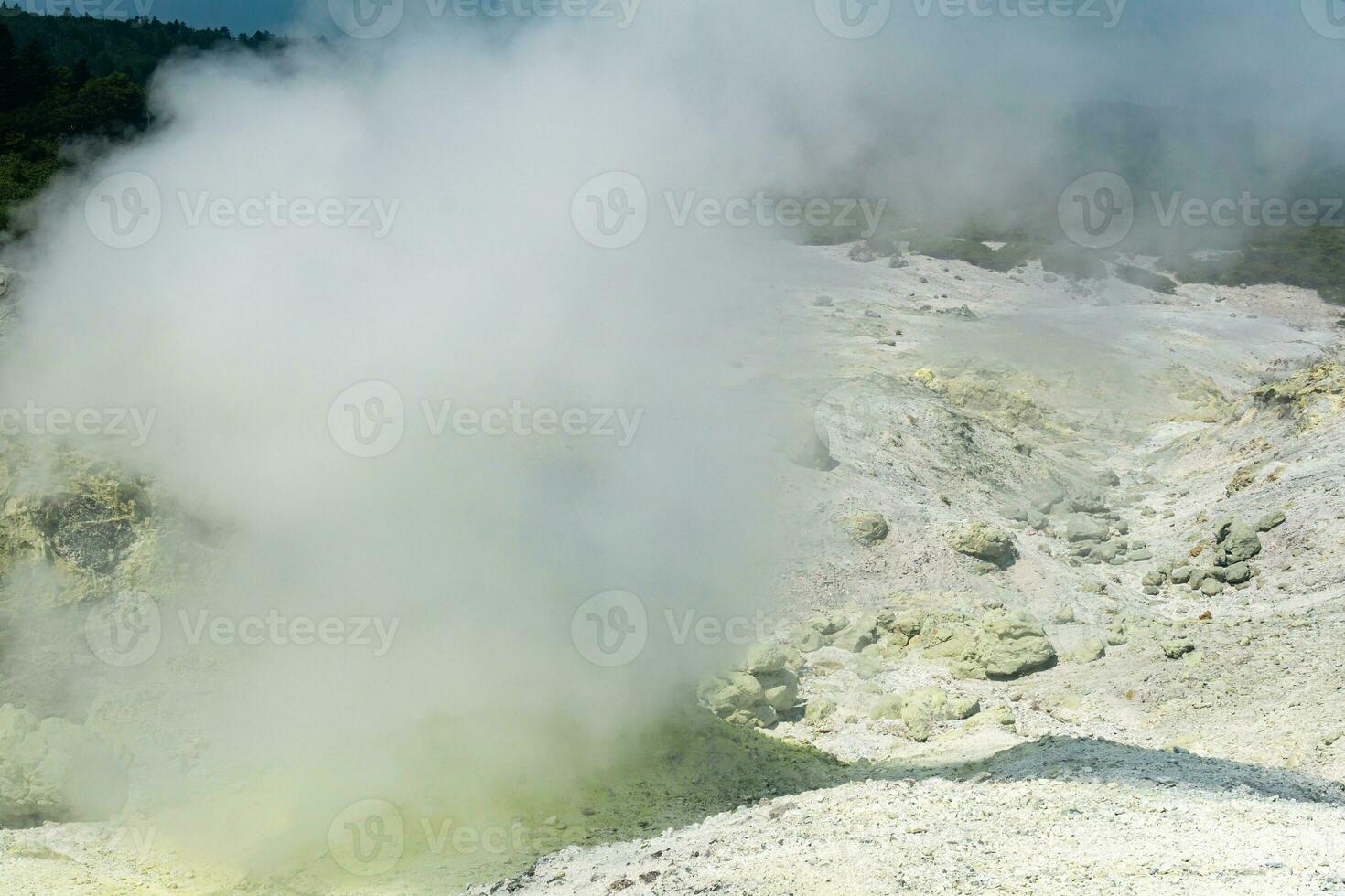 landscape of a fumarole field on the slope of a volcano is partially hidden by dense vapors photo