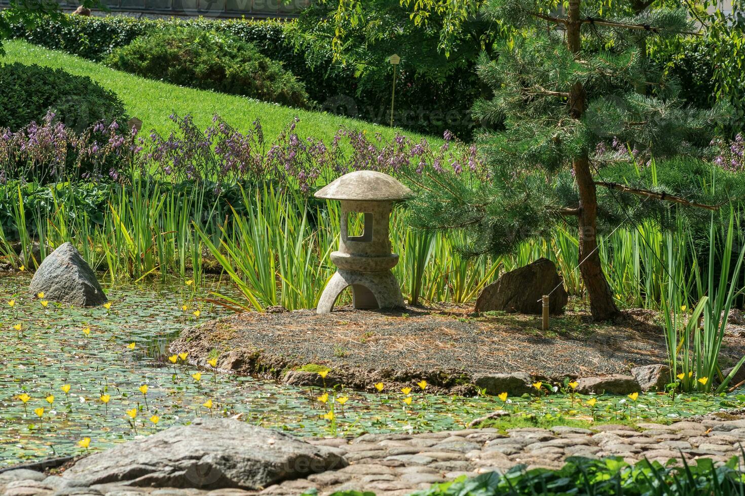 stone lantern on a small island in the middle of a pond in a Japanese garden photo