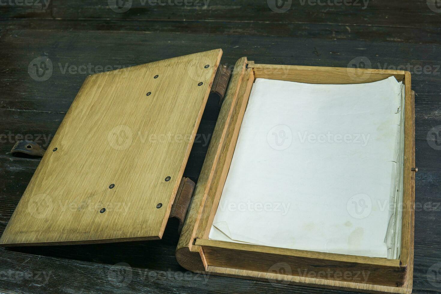 old log book in a wooden case with clasps on a black tabletop, opened photo