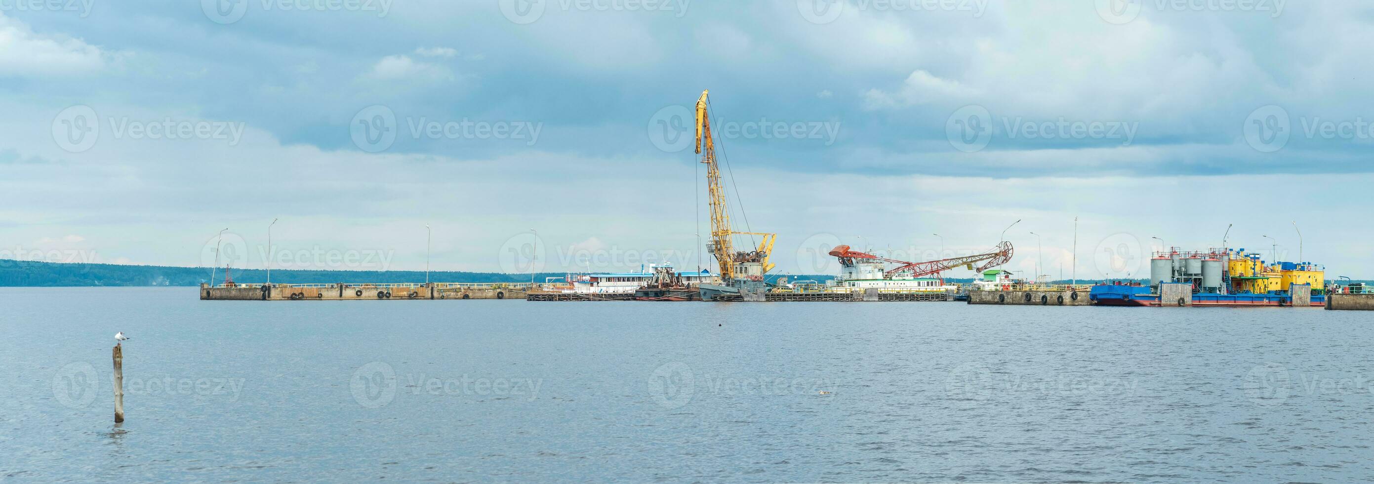 panorama de el carga muelle con grúas y técnico vasos en lluvioso día foto