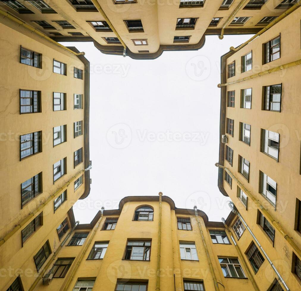 narrow and deep courtyard-well formed by closely standing walls of houses photo