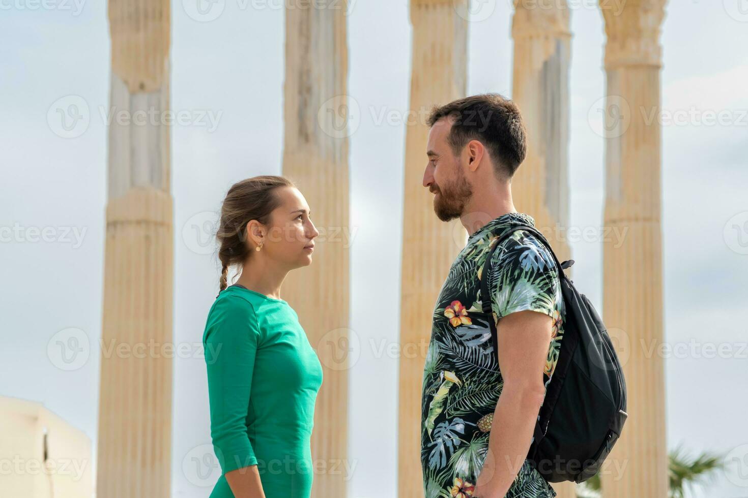 man and woman tourists look at each other against the background of ancient columns photo