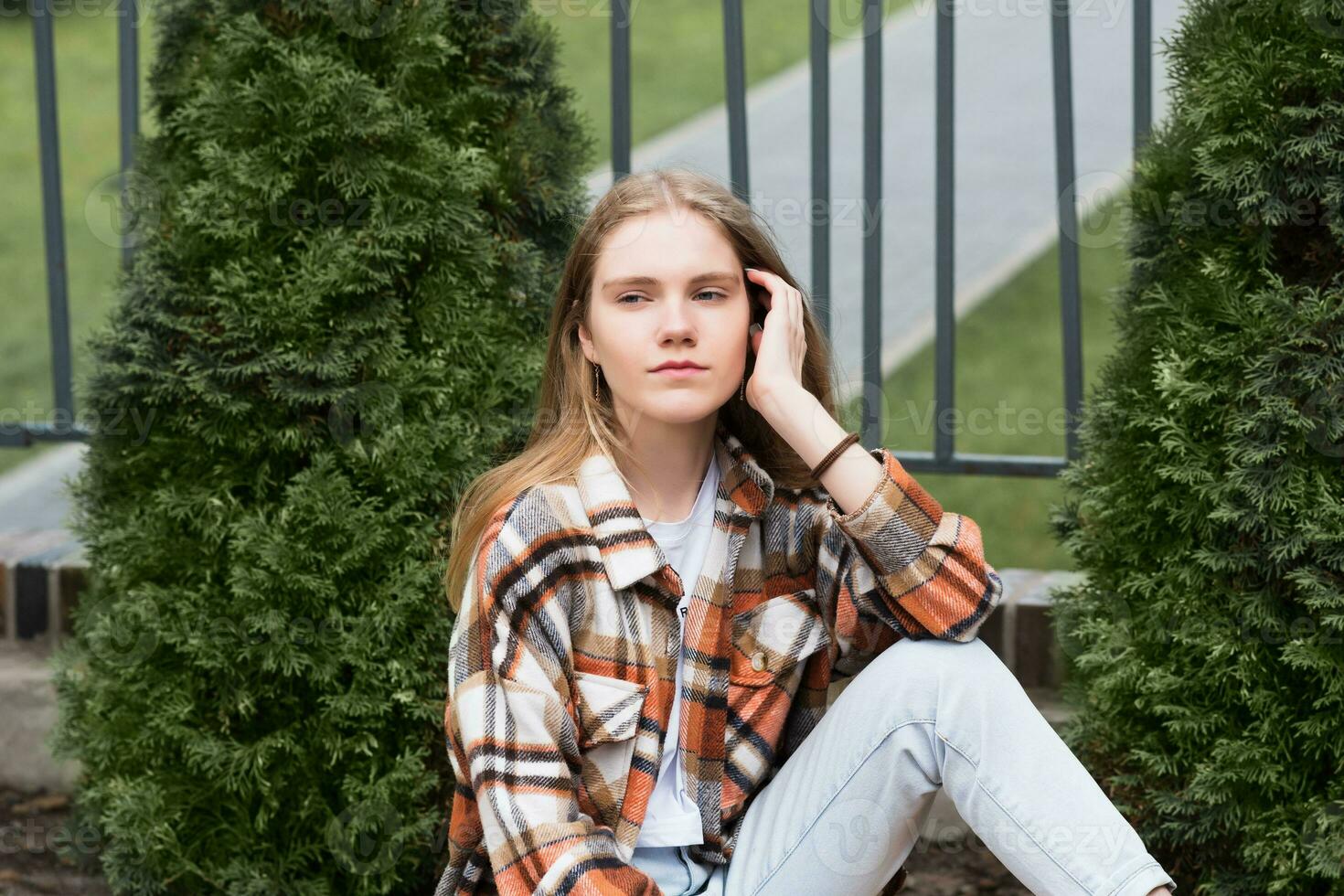 young woman sitting outdoors against a blurred urban background photo