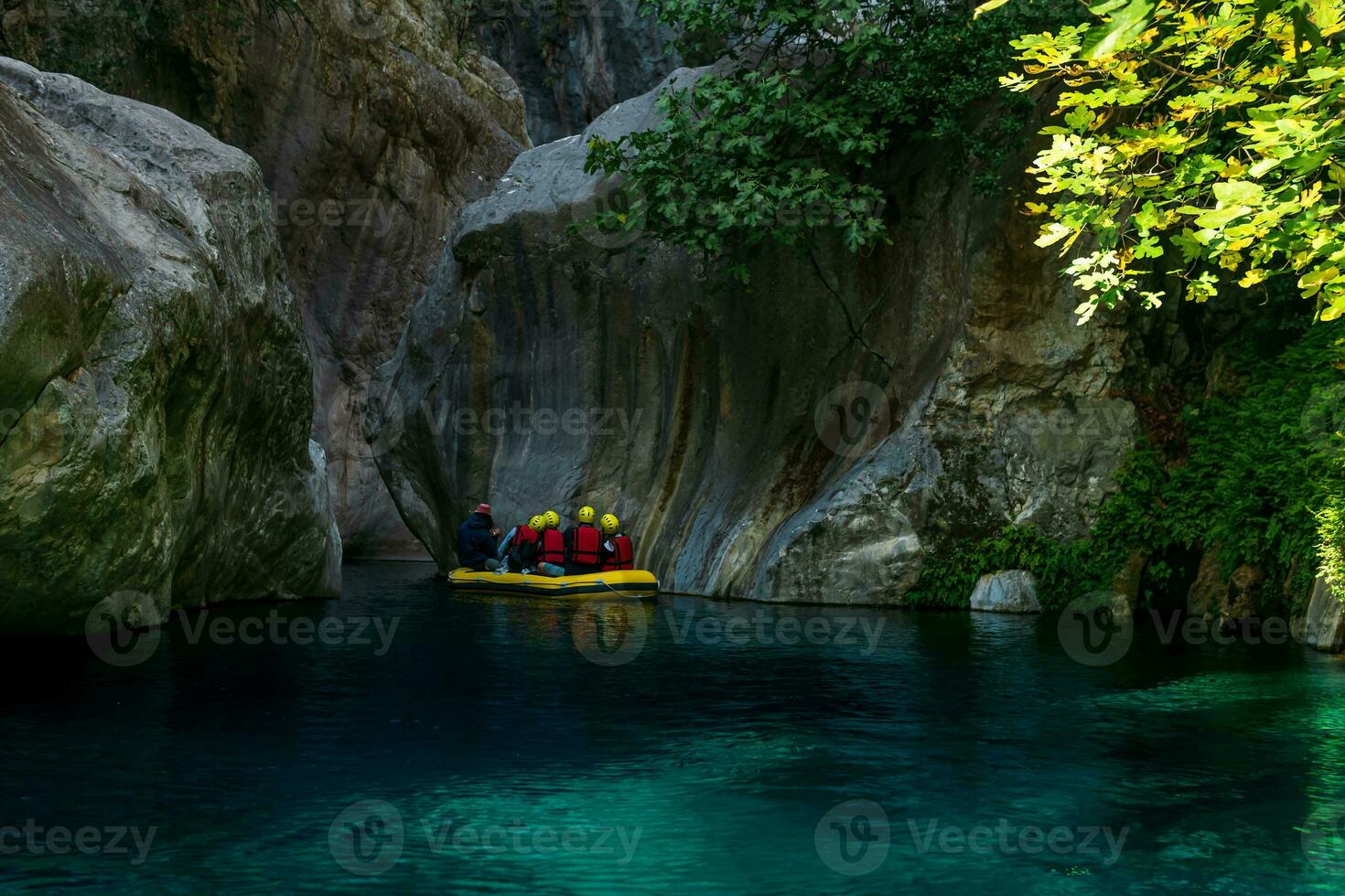 tourists on an inflatable boat float down a rocky canyon with blue water in Goynuk, Turkey photo