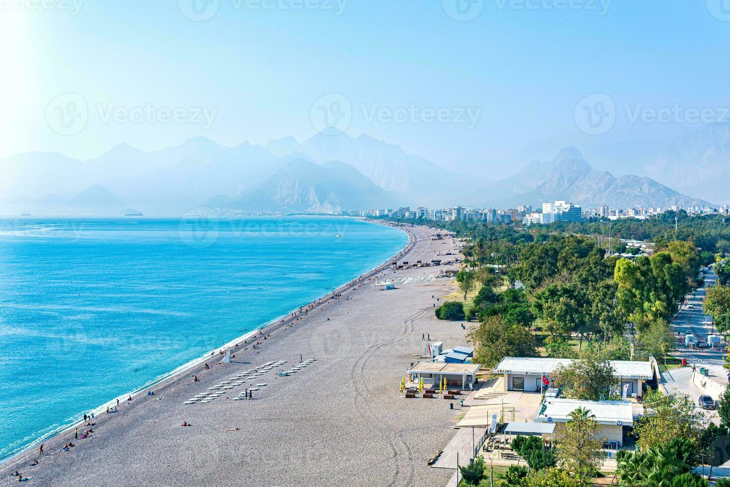 view of Konyaalti beach from nearby rocks in Antalya, Turkey. Beydaglari mountains in fog are visible in the background. photo