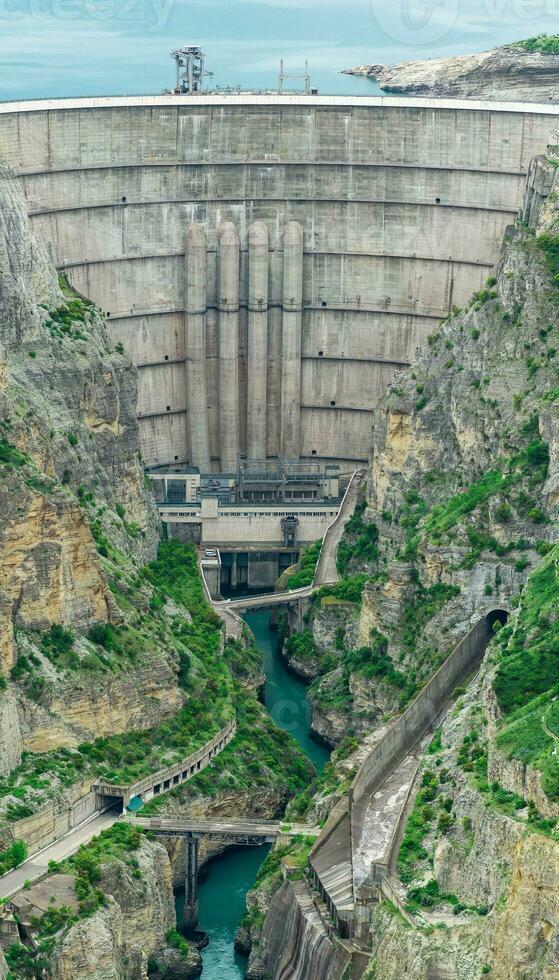 grande arco represa de un hidroeléctrico poder estación en un río en un rocoso cañón foto