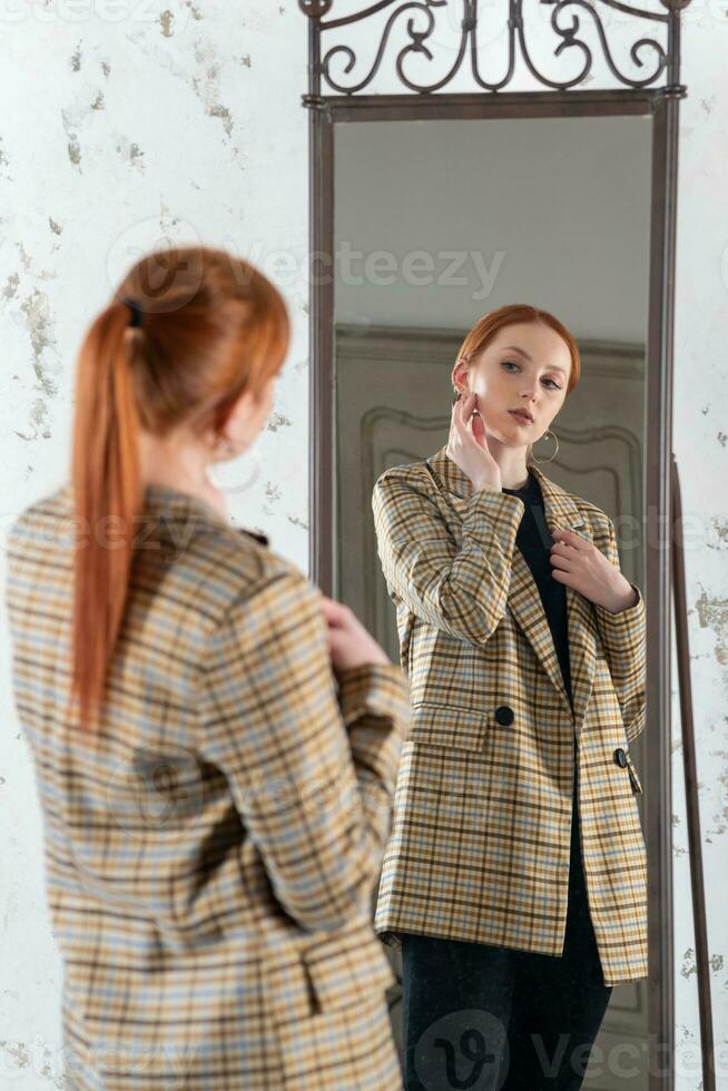 young red-haired woman in front of a full-length mirror photo