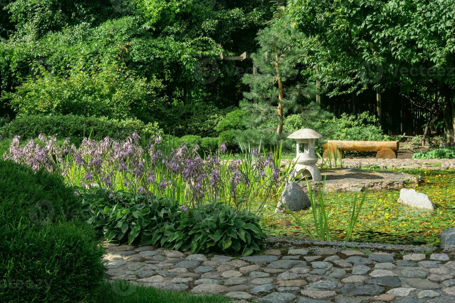 Roca linterna en un pequeño isla en el medio de un estanque en un japonés jardín foto