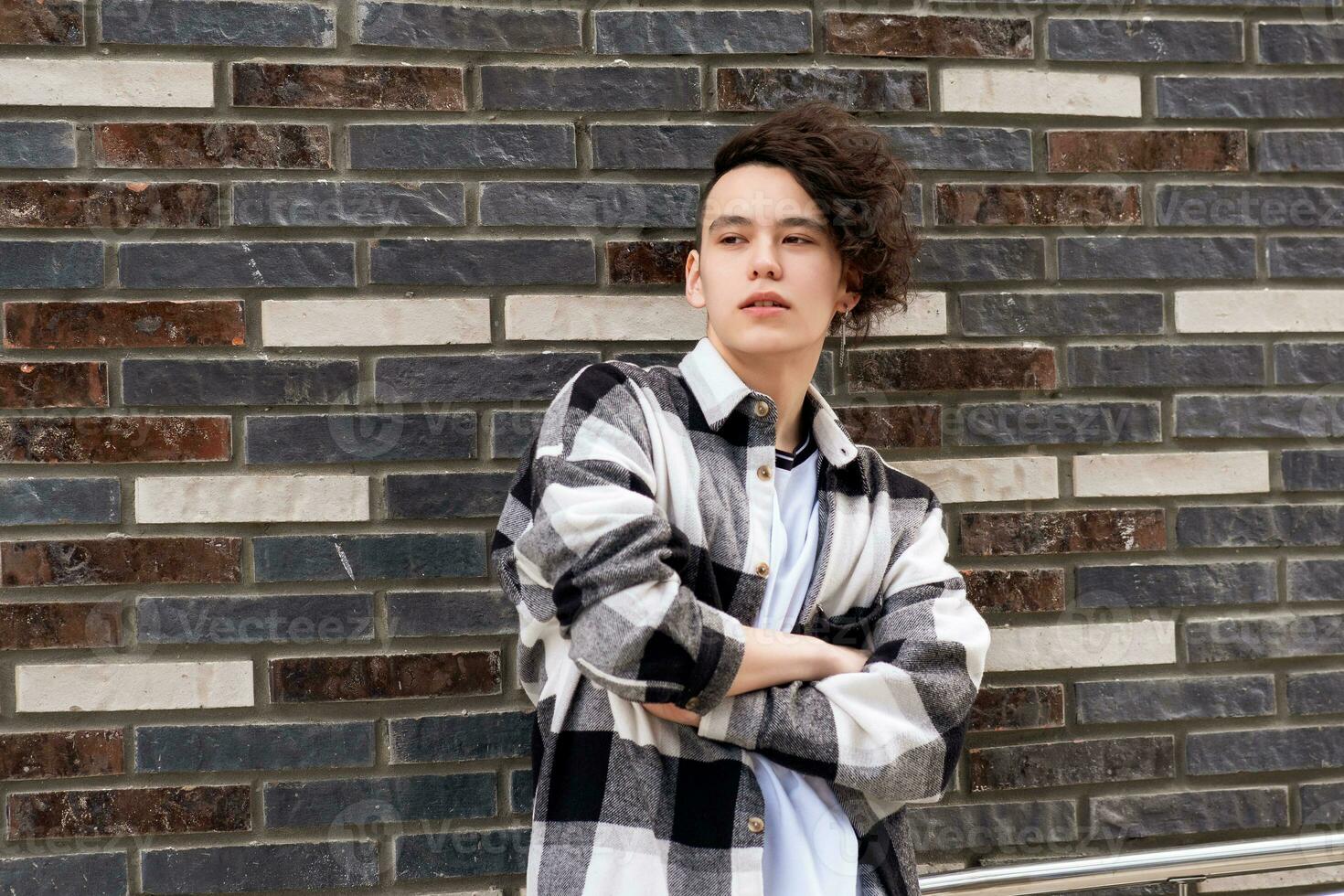 young man posing against a brick wall photo