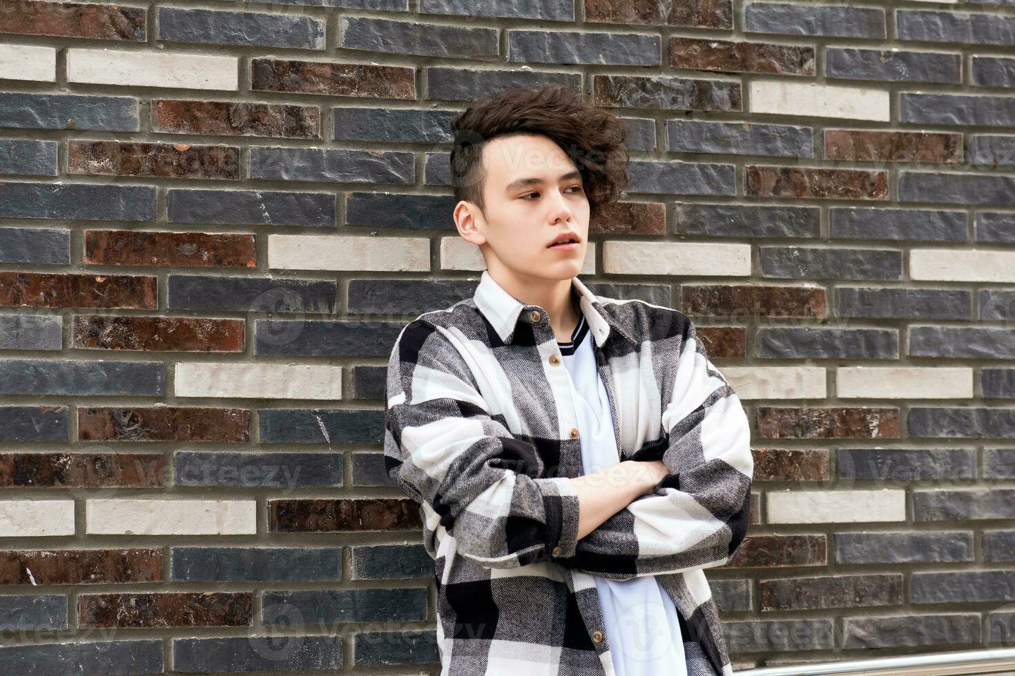 young man posing against a brick wall photo