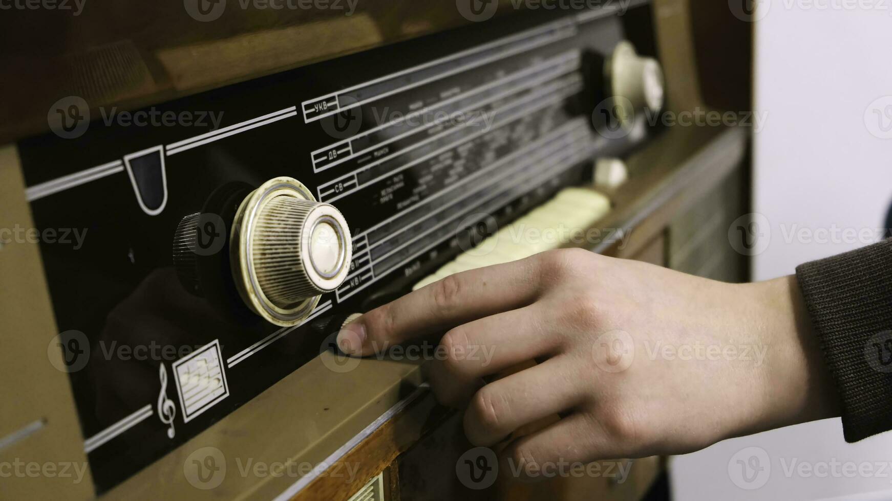 Close-up of man's hand rotating the knob on the old radio. Concept. Vintage technology photo