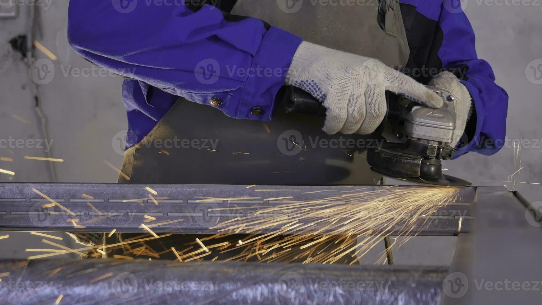 Craftsman sawing metal with disk grinder in workshop. Grinding metal with sparks flying. Electric wheel grinding on steel structure in factory Low speed shutter. Metal grinding with orange flying photo