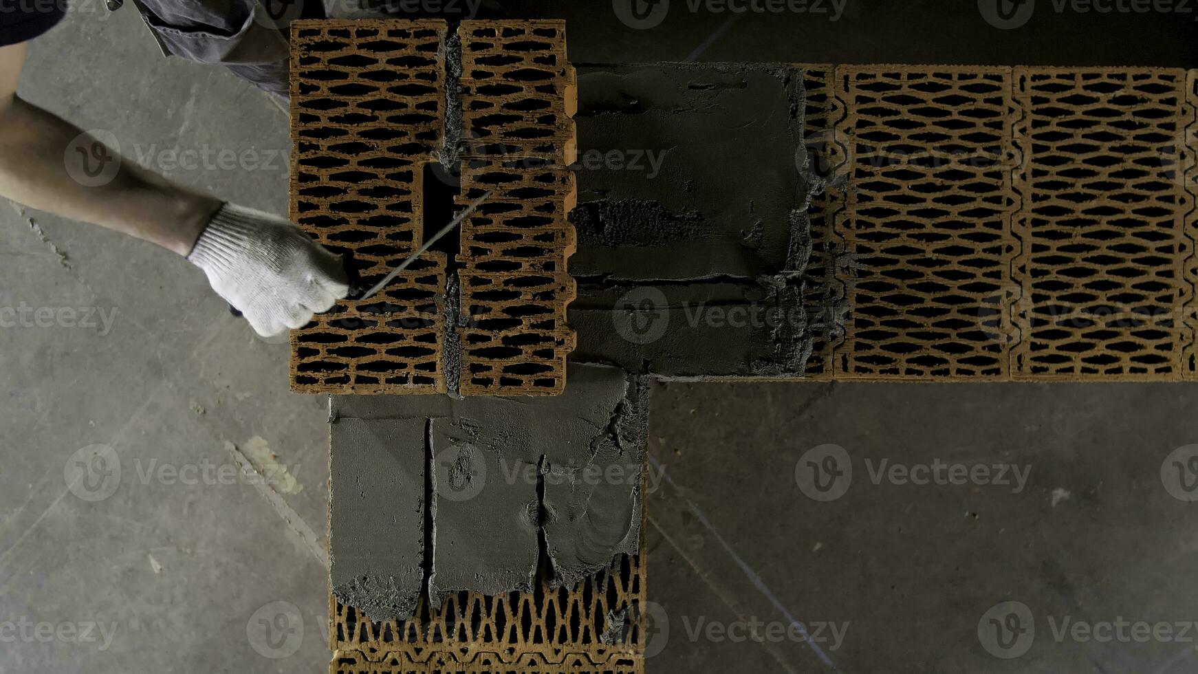 Bricklayers hands with in masonry trowel bricklaying new house wall on foundation. Stock footage. Bricklayer and mason working with bricks and building interior. photo