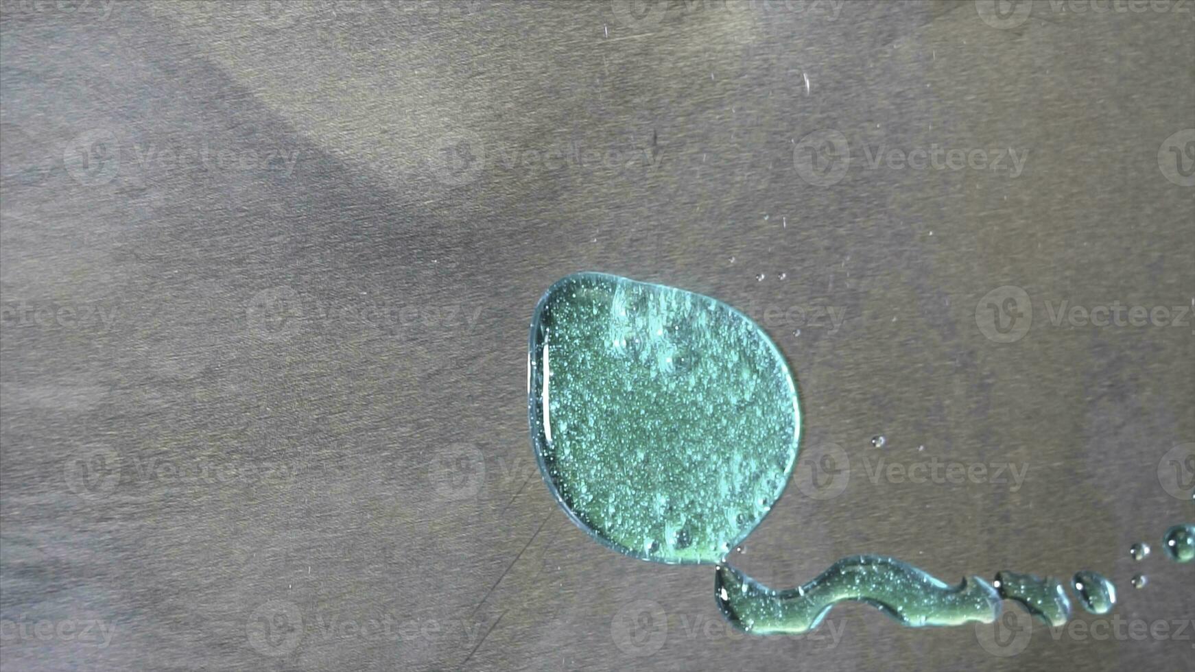 Top view of big turquoise stain on grey metal background holding stil. Big drop of bright teal paint with glowing particles on metal sheet surface. photo