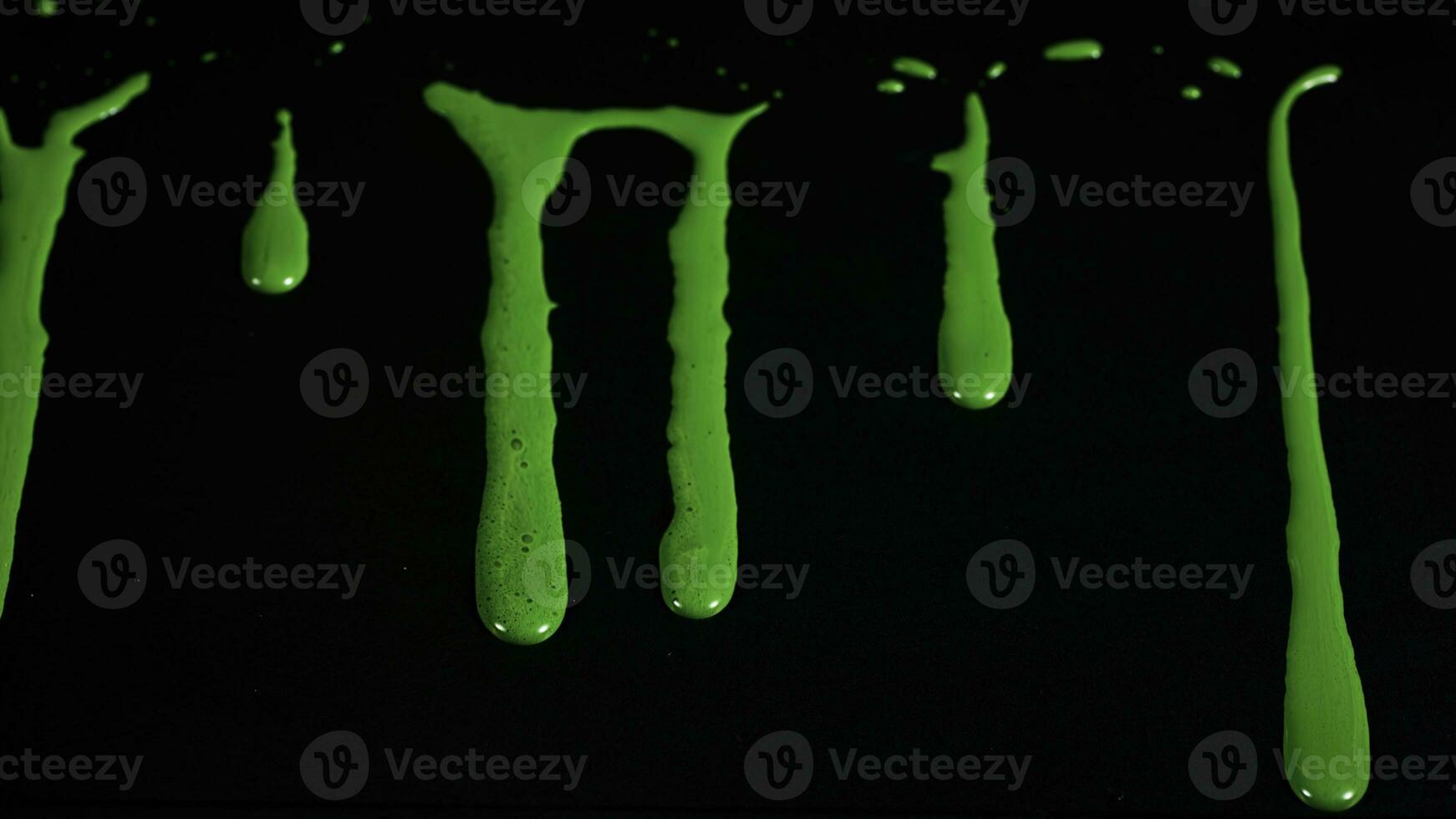 Drops and smudges of paint on glass. Stock footage. Bright acrylic paint drips on glass and runs down on black background. Paint flows on glass photo