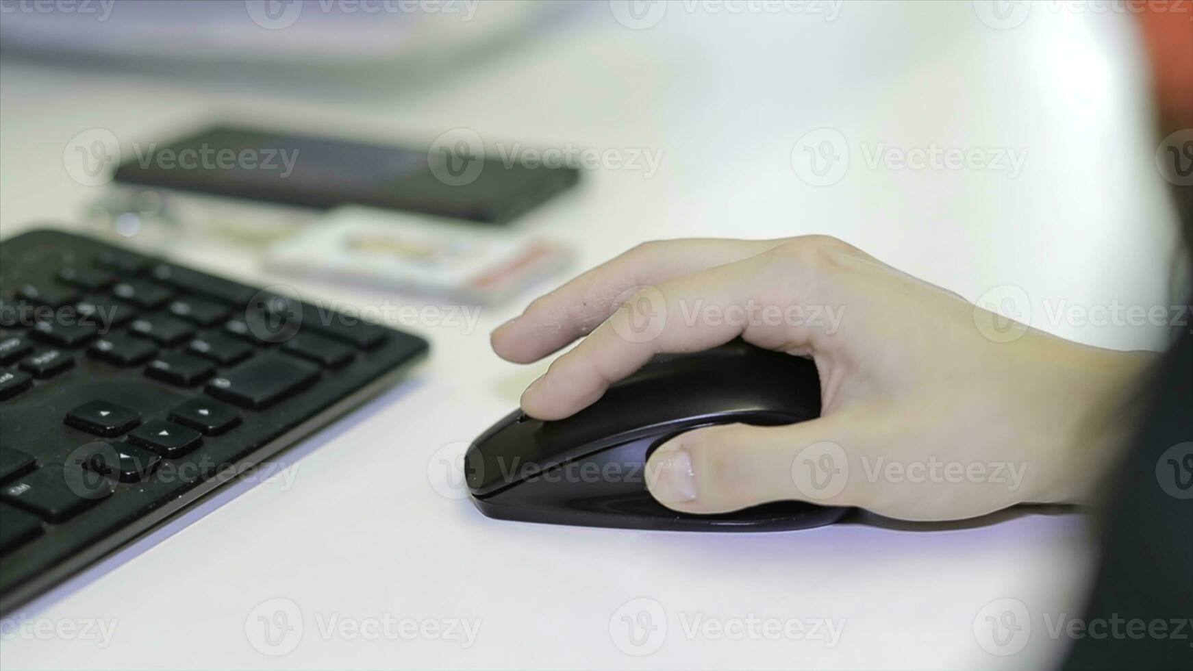 Close-up of female hand on black mouse. Woman's hand using cordless mouse on white table. Close up portrait of the hands of a young woman using a computer photo