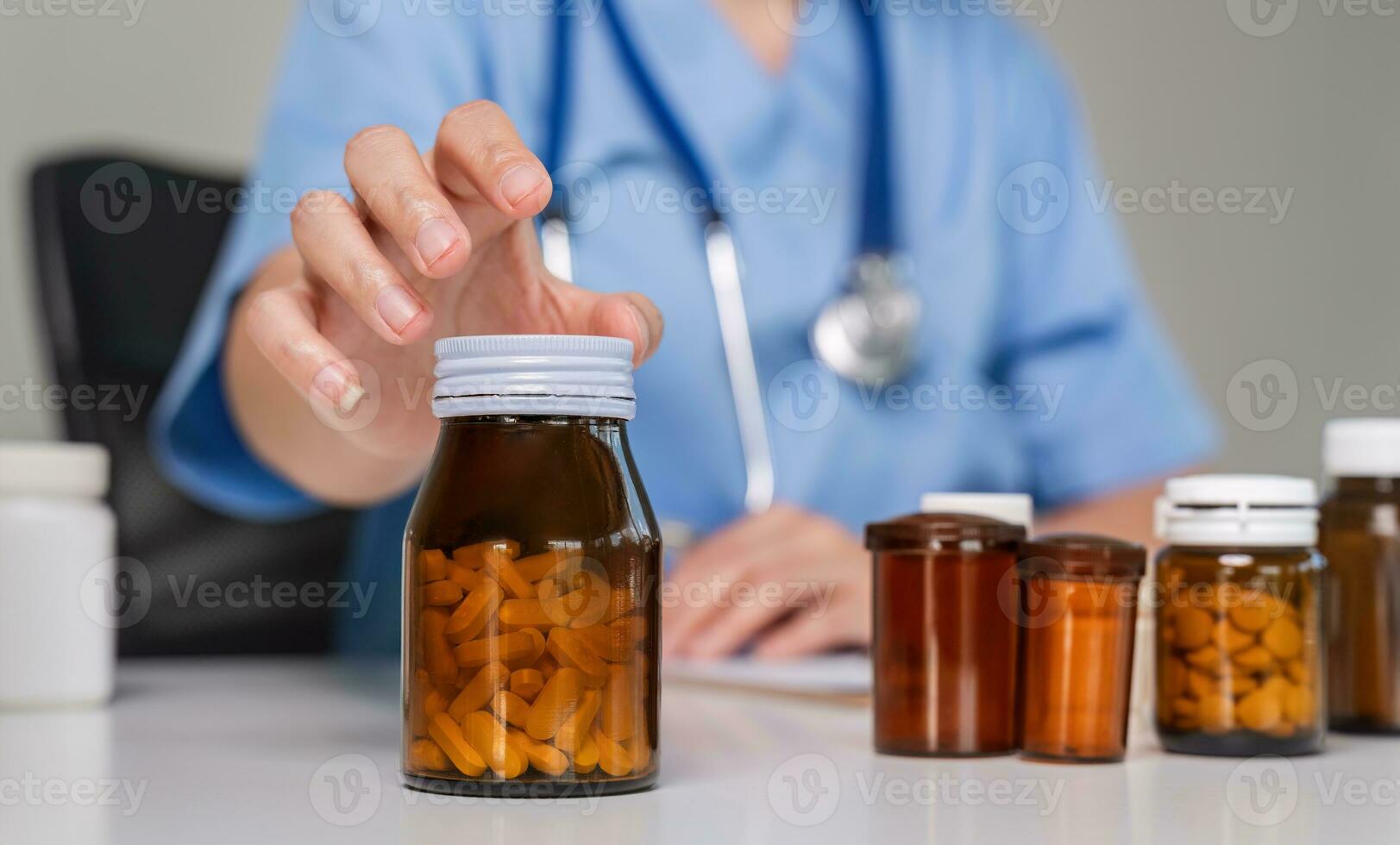 close up, Young Asian doctor in a white medical uniform with a stethoscope using a lab computer and tablet to organize and classify medicines in preparation for administration to patients. photo