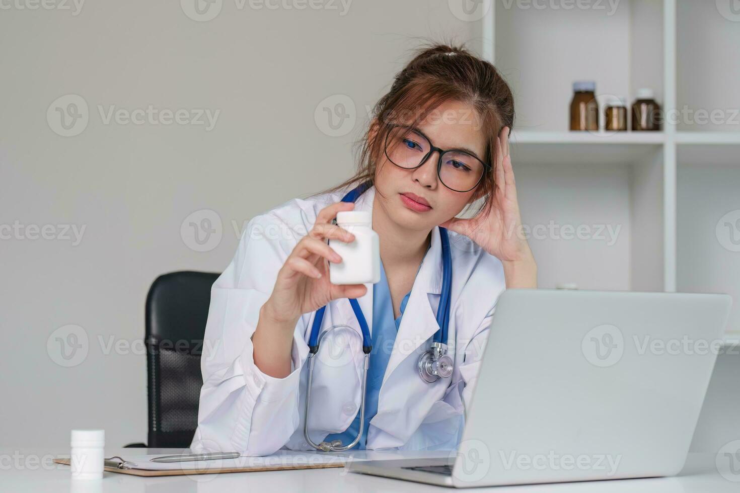 Stressed young female doctor looking at laptop, work related chaos, worried about mistake at work The stressed-out, unhappy medical professional is tired of solving computer problems at work. photo
