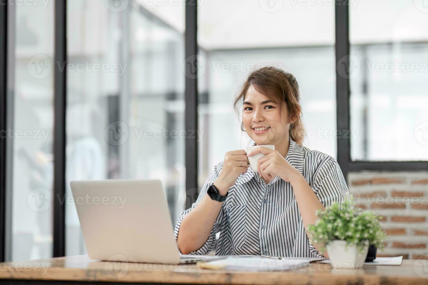 Businesswoman beautiful accountant working with paperwork holding cup of coffee while taking a break to relax working on finances project statistics from chart data. graphs on folders in the office photo