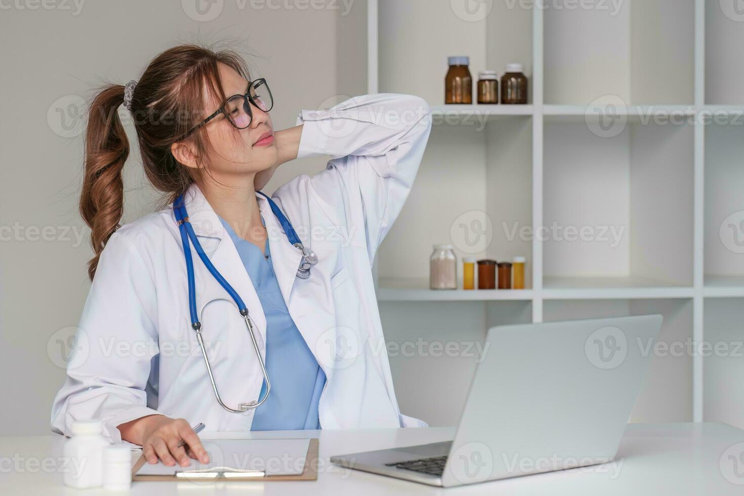 Stressed young female doctor looking at laptop, work related chaos, worried about mistake at work The stressed-out, unhappy medical professional is tired of solving computer problems at work. photo