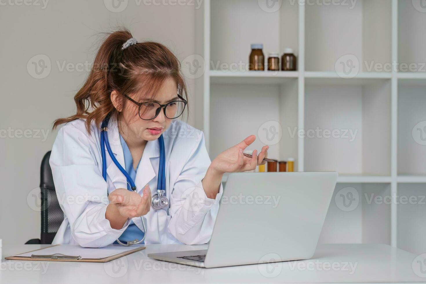 Stressed young female doctor looking at laptop, work related chaos, worried about mistake at work The stressed-out, unhappy medical professional is tired of solving computer problems at work. photo