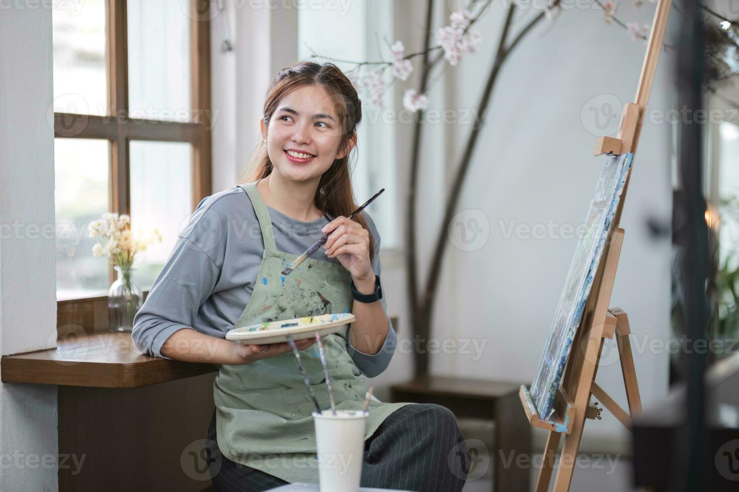 Portrait of a young female artist working on an abstract acrylic canvas painting in an art painting studio. photo