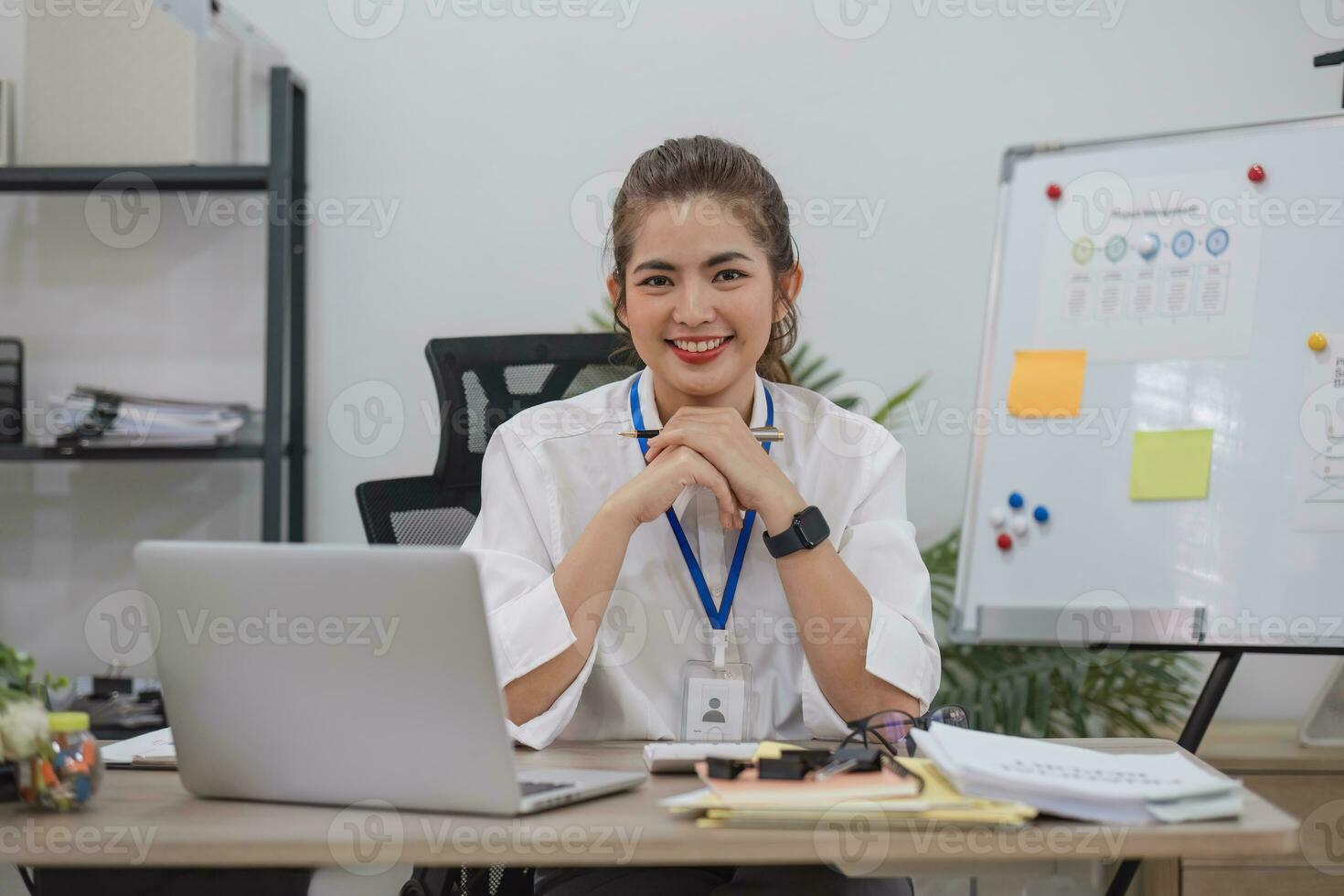 Charming Asian businesswoman working with a laptop at the office. Looking at camera. photo