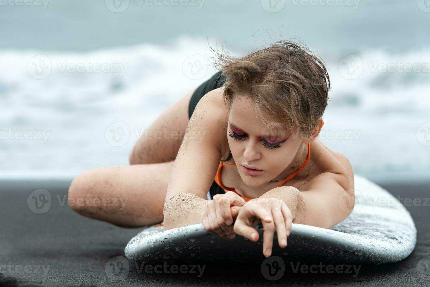 Close-up view of woman surfer lying on surfboard with eyes closed, looks so relaxed and peaceful photo