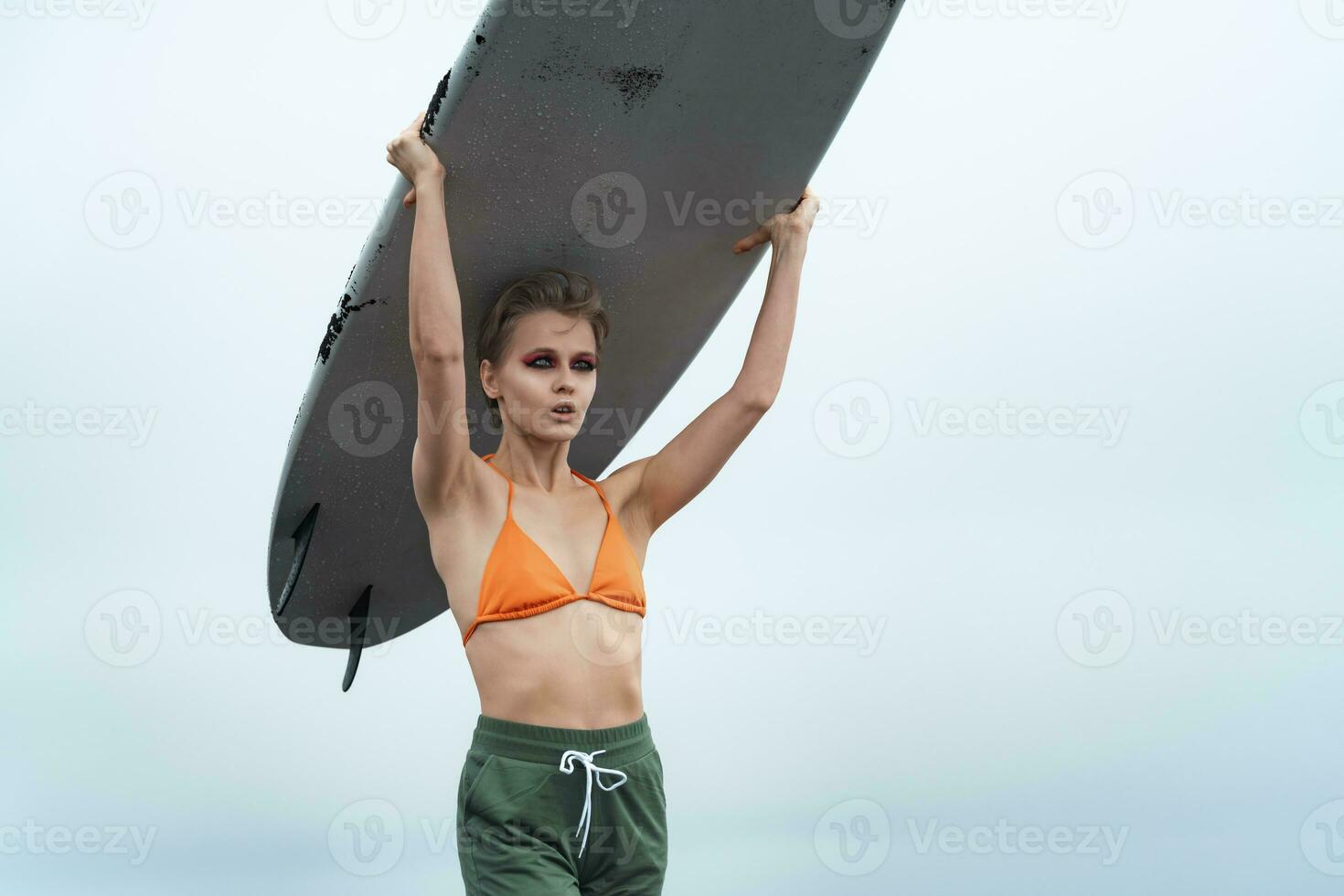Close-up view of woman surfer carrying white surfboard on her head during summer holiday photo