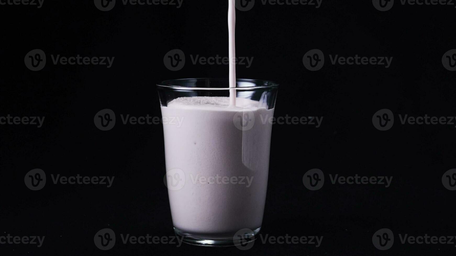 Close-up of clean glass filled by strawberry milkshake. Frame. Isolated on black photo