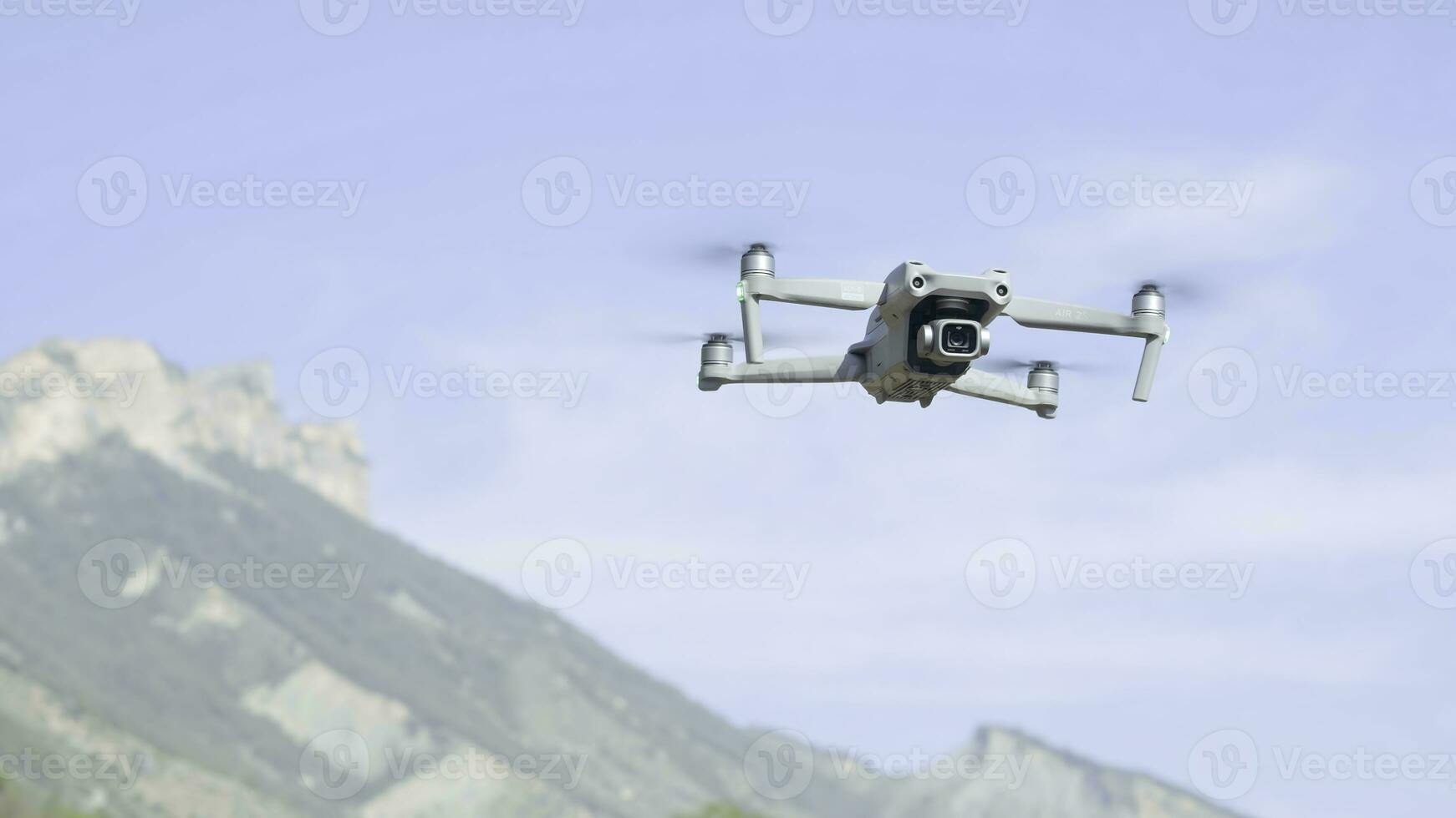 Aerial view of a quadcopter flying above green mountains on morning haze background. Action. Drone filming video of natural landscape. photo