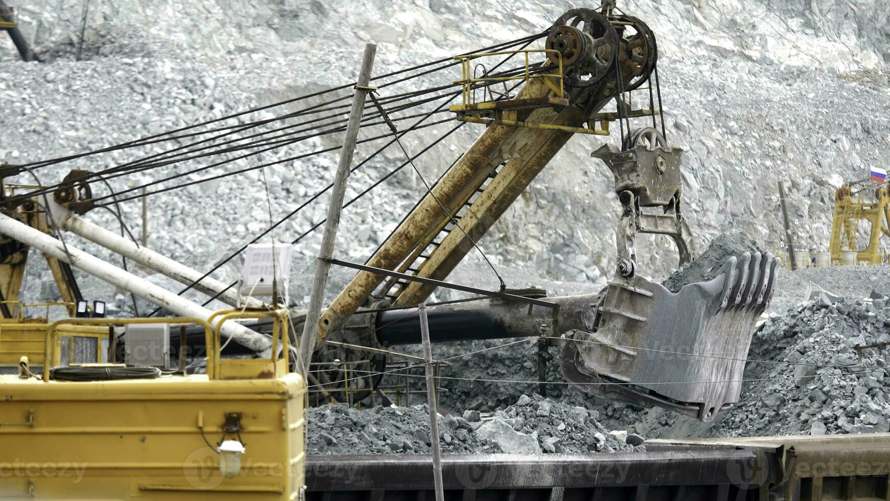 Excavator and railway with ore. Excavator fills with ore rail cars in background of open pit. Heavy transport in mining industry photo