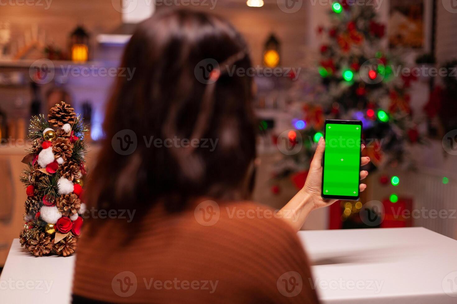 Festive person holding smartphone with green screen for modern technology on mockup template. Caucasian young woman watching digital device with chroma key to view background design photo