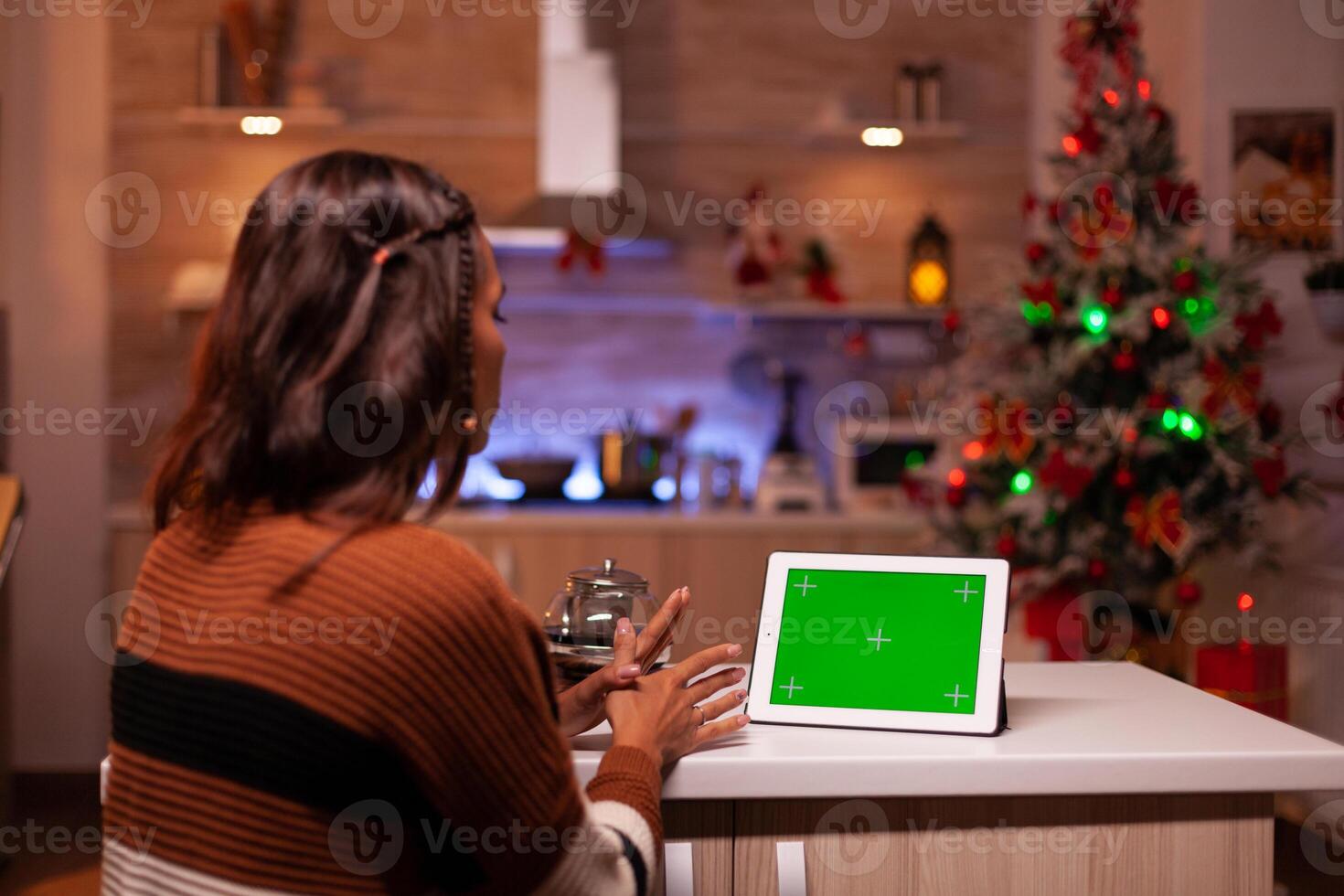 Young person watching green screen technology on tablet in kitchen at home. Caucasian woman using digital chroma key concept for background template, mockup gadget app on virtual display photo