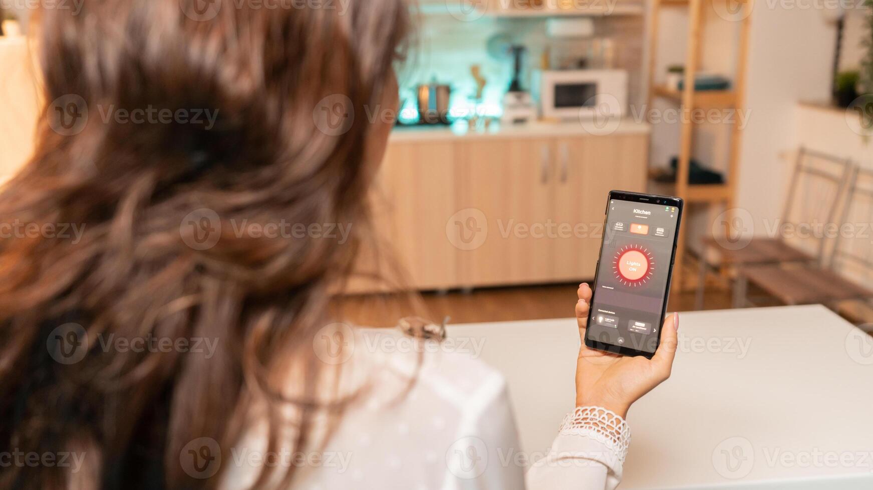 Woman hands holding phone with smart app for home lighting. Person in apartment holding telephone with touchscreen and app for lights. photo