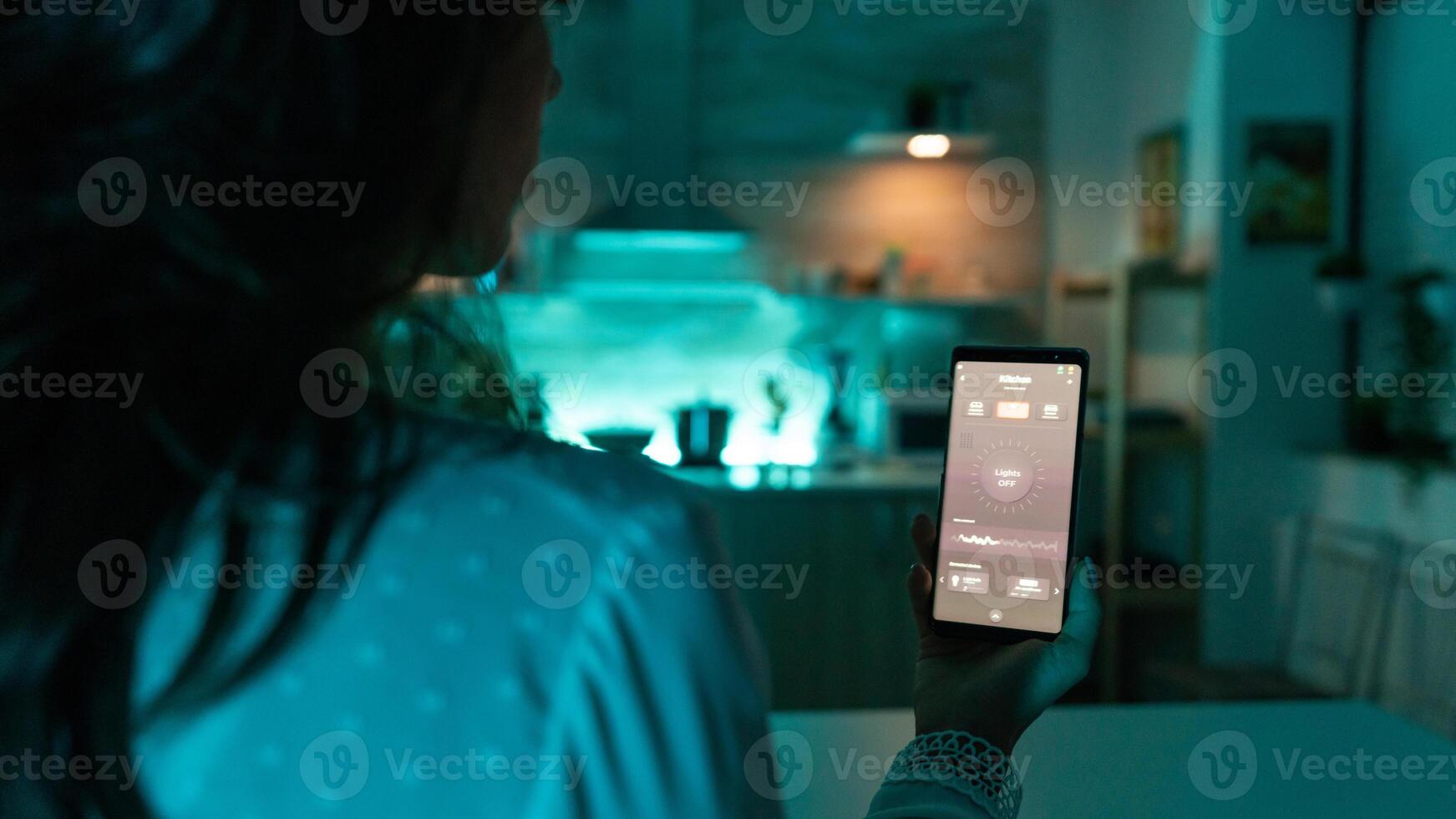 Woman using automation phone app to change light color remotely. Person in apartment holding telephone with touchscreen and app for lights. photo