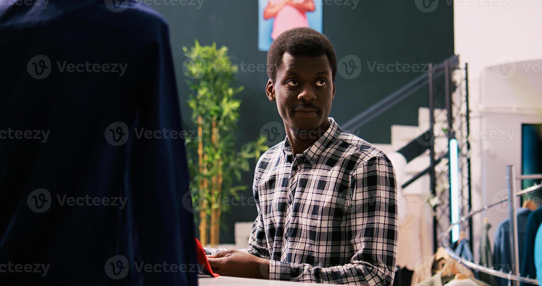 Portrait of customer smiling during shopping session, analyzing elegant tie in modern boutique. African american man shopping for stylish merchandise and trendy accessories in clothing store photo