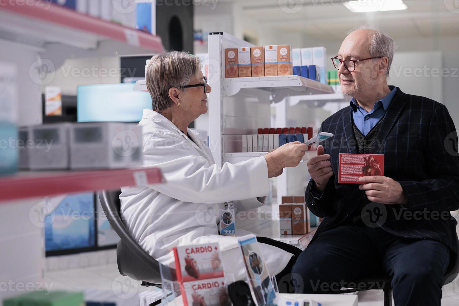 Senior drugstore client selecting heart health supplements in pharmacy store and discussing disease prevention with pharmaceutical employee. Elderly man getting professional consultation in apothecary photo
