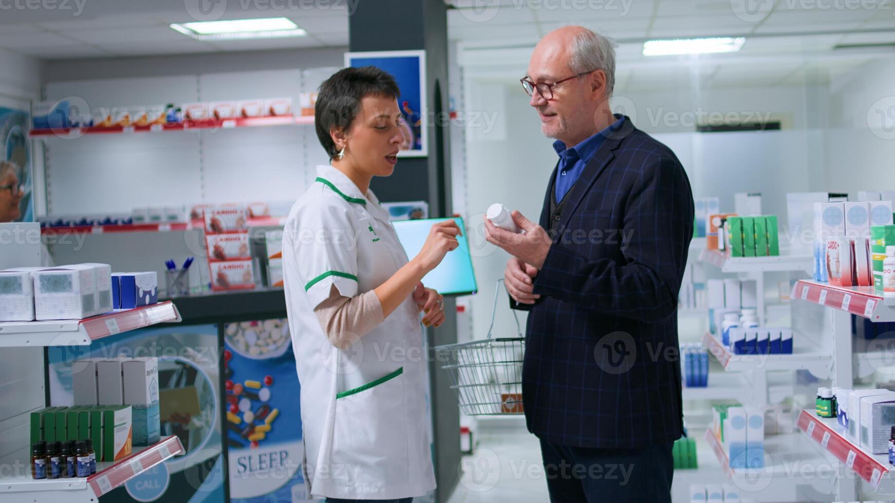 Tracking camera shot of elderly man holding shopping basket entering chemist store looking to purchase heart attack prevention medication pills, asking professional pharmacist for help photo