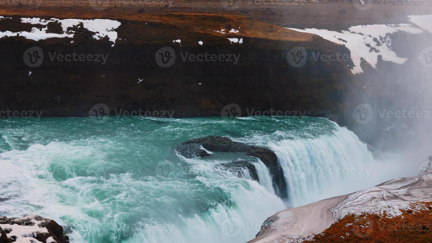 Majestic water stream in iceland with snowy nature and hills, gullfoss waterfall in reykjavik. Beautiful large river flow cascade with scandinavian nordic landscapes. Handheld shot. photo