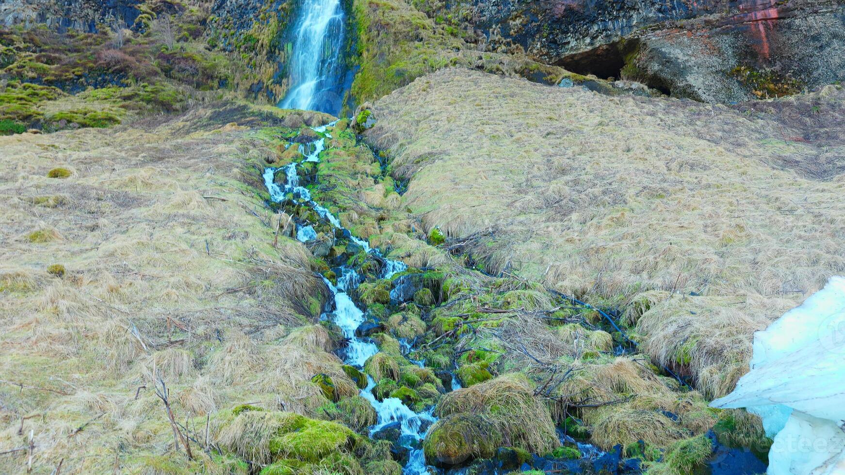 River stream from scandinavian cascade flowing down off of hill, water flow running off cliff in iceland. Beautiful seljalandsfoss waterfall in reykjavik, arctic landscape. Handheld shot. photo