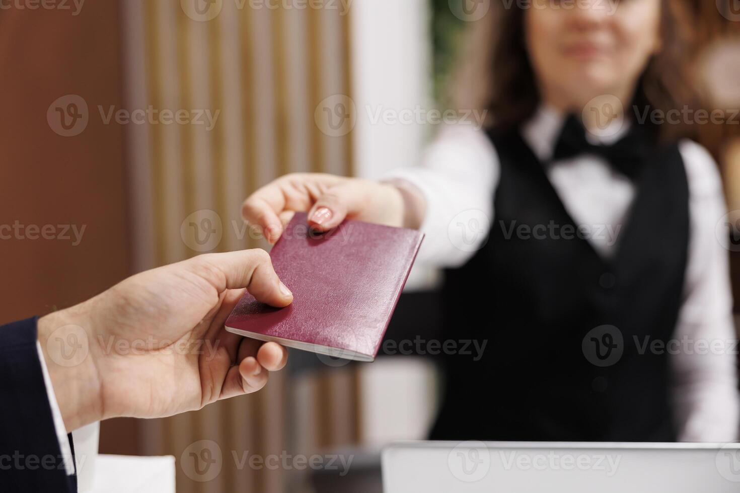 Businessman providing passport for check in process, giving identification documents to receptionist at front desk. Adult arriving at hotel for registration, id papers in lobby. Close up. photo