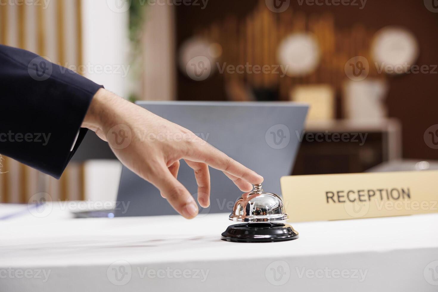 Business traveller rings service bell at reception counter, calling for employees assistance after arriving at luxury hotel. Businessman using bell at front desk, ready for check in. Close up. photo